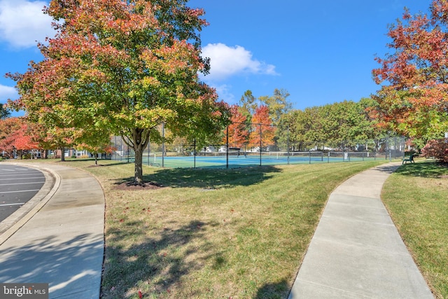 view of home's community featuring a lawn and tennis court