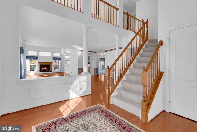 foyer entrance featuring ornate columns, a high ceiling, and light wood-type flooring