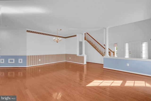 unfurnished living room featuring wood-type flooring, an inviting chandelier, and a high ceiling