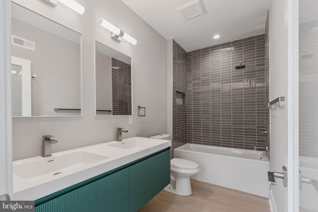 full bathroom with vanity, toilet, wood-type flooring, and tiled shower / bath