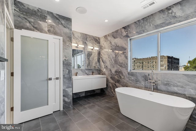 bathroom featuring vanity, tile walls, a wealth of natural light, and a washtub