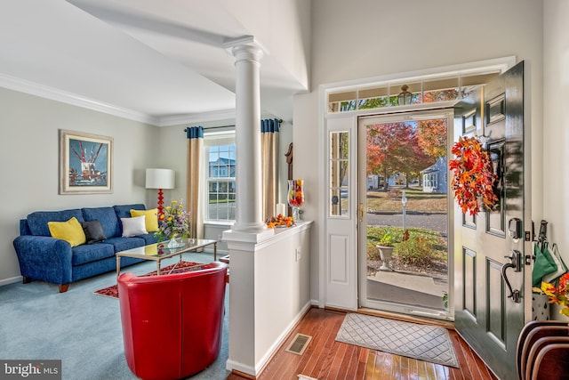 entrance foyer with crown molding, decorative columns, and light hardwood / wood-style flooring