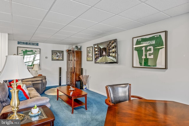 living room featuring a drop ceiling and carpet