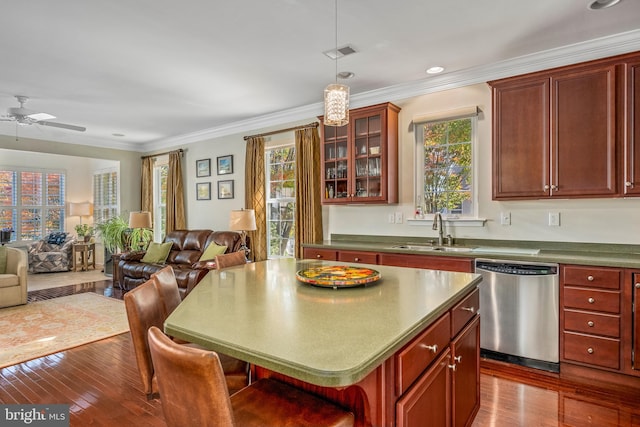 kitchen with hardwood / wood-style flooring, stainless steel dishwasher, ornamental molding, sink, and decorative light fixtures