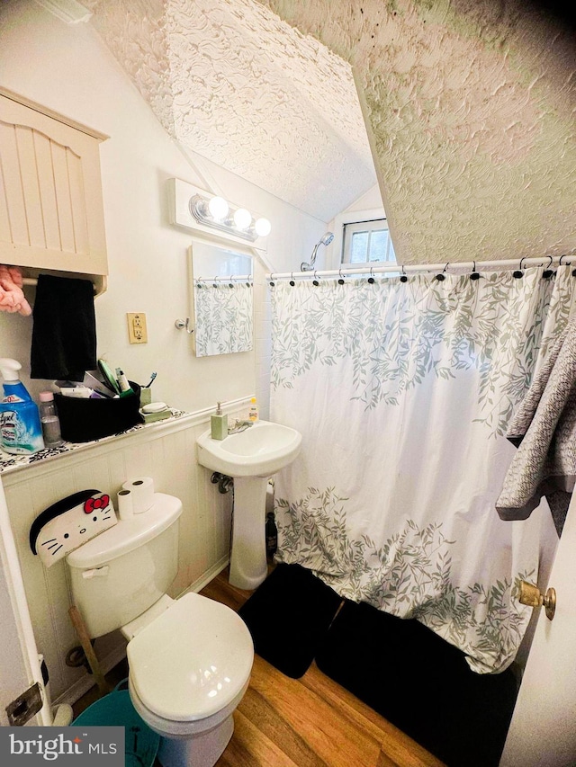 bathroom with walk in shower, a textured ceiling, hardwood / wood-style floors, toilet, and lofted ceiling