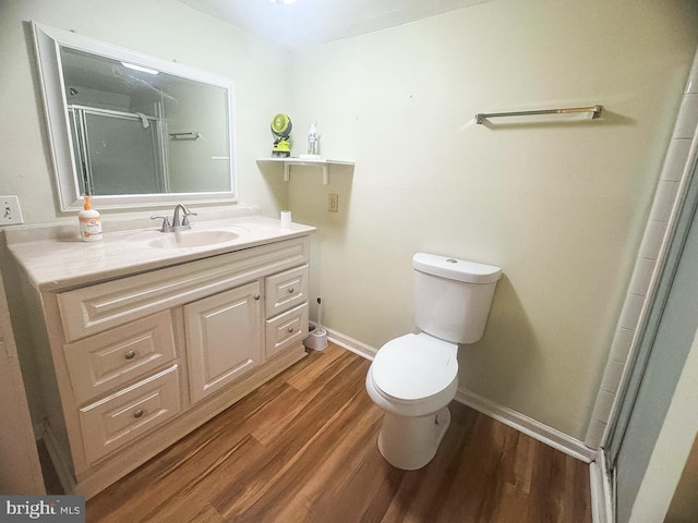 bathroom with toilet, an enclosed shower, vanity, and hardwood / wood-style floors