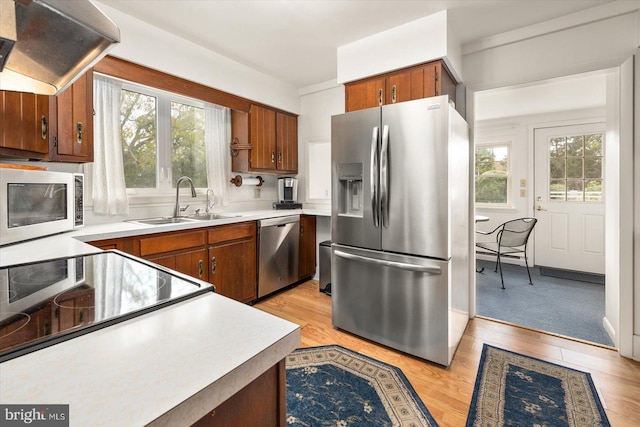 kitchen with stainless steel appliances, extractor fan, light hardwood / wood-style flooring, and plenty of natural light