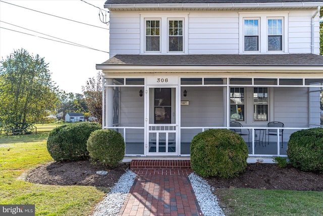 view of front of house with covered porch, a front lawn, and a shingled roof