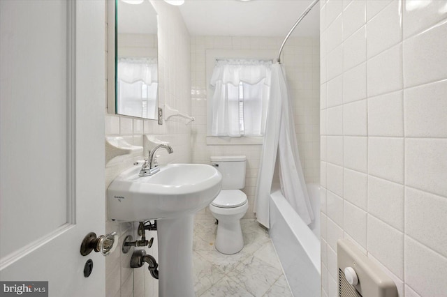 bathroom with shower / tub combo, toilet, marble finish floor, and tile walls