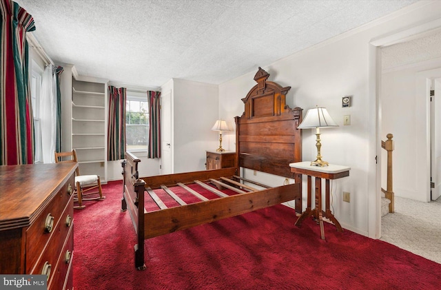 carpeted bedroom with baseboards, a textured ceiling, and crown molding