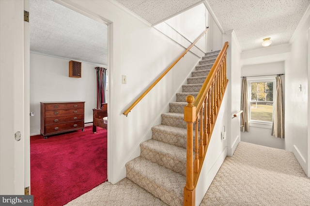 stairs with ornamental molding, carpet floors, and a textured ceiling