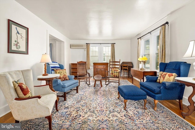 sitting room with a wall mounted air conditioner and hardwood / wood-style floors