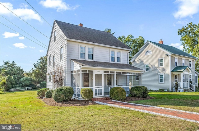 view of front of home with roof with shingles, a chimney, a front lawn, and a sunroom