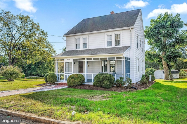traditional home featuring a chimney, a storage unit, a shingled roof, an outbuilding, and a front lawn