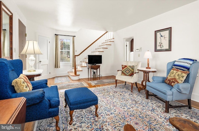 living area with wood finished floors, baseboards, and stairs