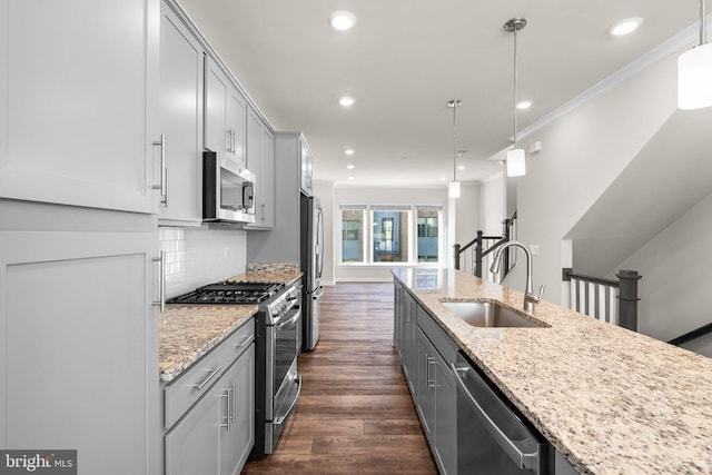 kitchen with dark wood-type flooring, stainless steel appliances, sink, light stone countertops, and decorative light fixtures