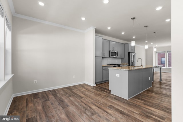 kitchen with a kitchen island with sink, gray cabinetry, decorative light fixtures, appliances with stainless steel finishes, and light stone counters