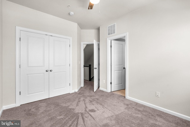 unfurnished bedroom featuring a closet, light colored carpet, and ceiling fan