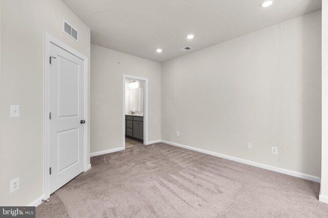 unfurnished bedroom featuring light colored carpet and connected bathroom