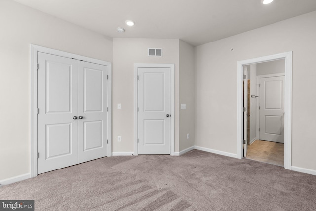 unfurnished bedroom featuring light colored carpet and a closet