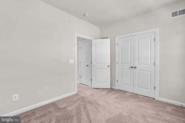 unfurnished bedroom featuring light colored carpet and a closet