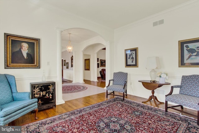 living area featuring ornamental molding, hardwood / wood-style floors, and ornate columns