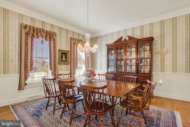 dining area featuring ornamental molding, a notable chandelier, and hardwood / wood-style floors