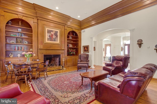 living room featuring ornamental molding, ornate columns, wood-type flooring, and built in features