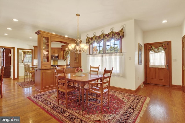 dining space with a wealth of natural light, an inviting chandelier, and light wood-type flooring