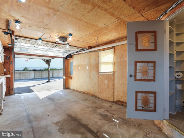 garage with wood ceiling, wood walls, and electric panel