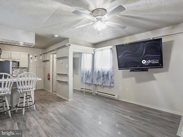 kitchen featuring white cabinets, a baseboard radiator, ceiling fan, a textured ceiling, and hardwood / wood-style flooring