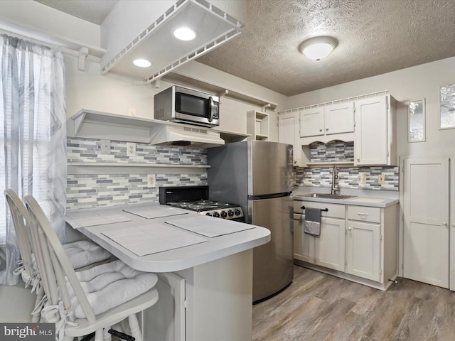 kitchen with a breakfast bar area, white cabinets, kitchen peninsula, and stainless steel appliances