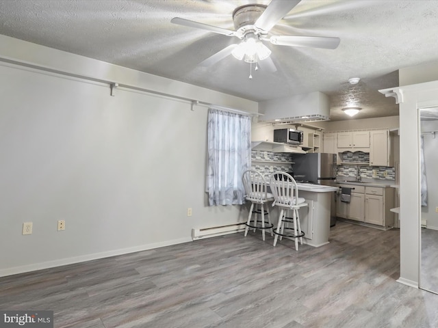 kitchen featuring a kitchen breakfast bar, white cabinetry, a textured ceiling, and light wood-type flooring