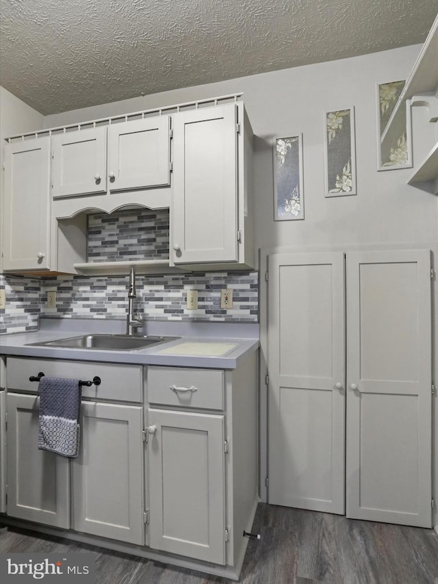 kitchen featuring white cabinetry, sink, dark wood-type flooring, and backsplash