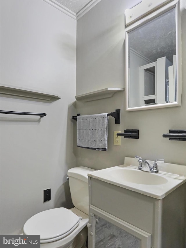 bathroom with toilet, crown molding, a textured ceiling, and vanity