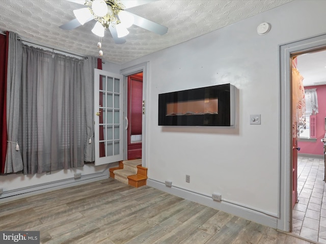 empty room featuring light hardwood / wood-style floors, a textured ceiling, a baseboard heating unit, and ceiling fan