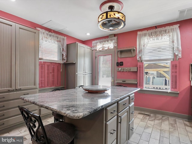 kitchen featuring dark stone counters, a kitchen bar, and a kitchen island