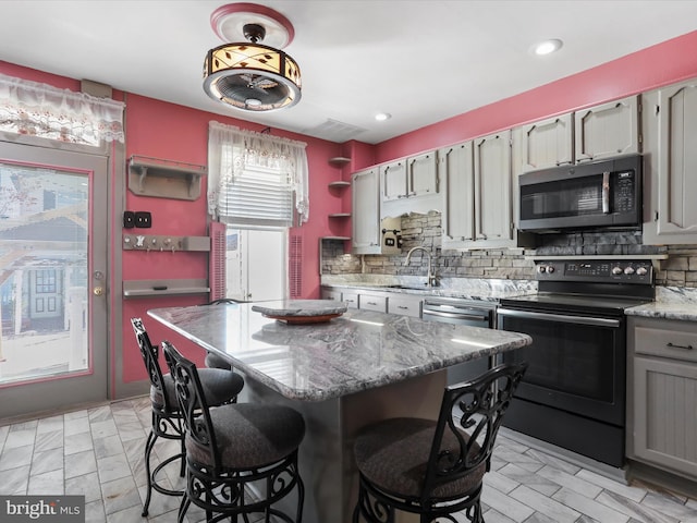 kitchen featuring tasteful backsplash, stainless steel appliances, sink, and a kitchen island