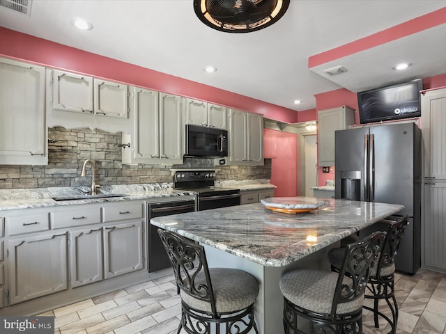 kitchen featuring a center island, black appliances, sink, and backsplash