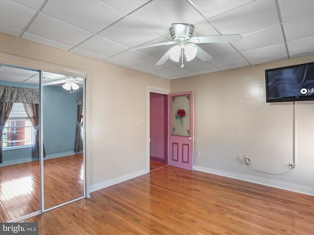 interior space with a paneled ceiling, wood-type flooring, and ceiling fan