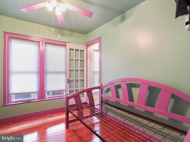 bedroom with ceiling fan, a textured ceiling, wood-type flooring, and multiple windows