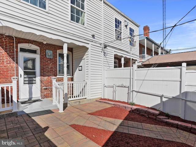 exterior space with fence, a porch, a gate, and brick siding