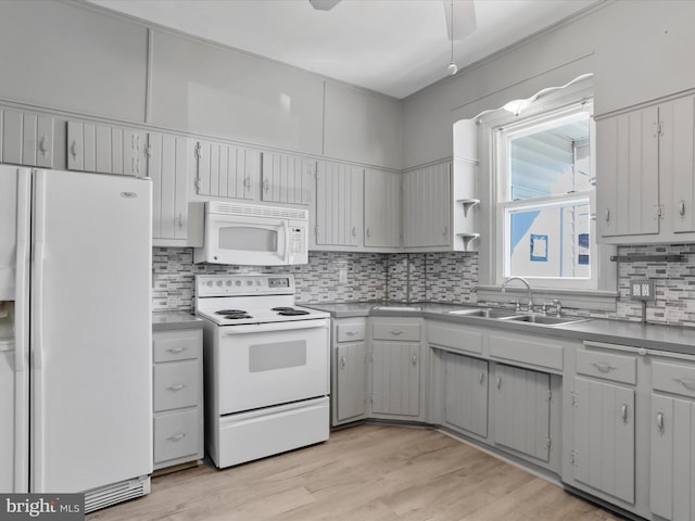 kitchen with white appliances, backsplash, sink, and light wood-type flooring