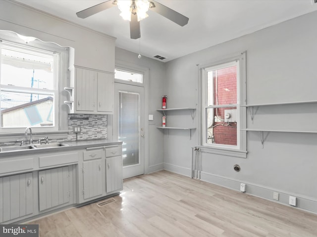 kitchen featuring backsplash, sink, light hardwood / wood-style floors, and ceiling fan