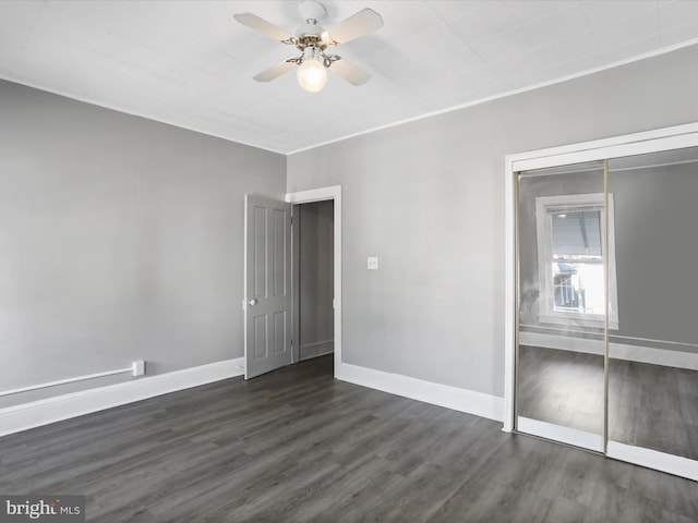 unfurnished bedroom with a closet, dark hardwood / wood-style floors, and ceiling fan