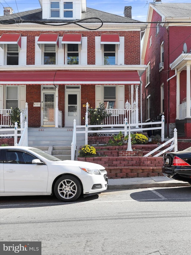 townhome / multi-family property with cooling unit and a porch