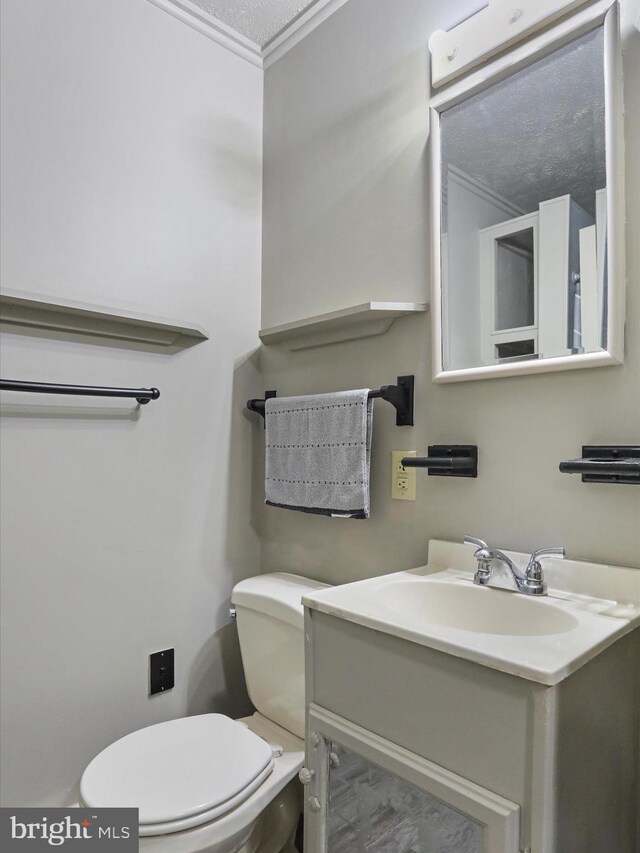 bathroom with vanity, toilet, crown molding, and a textured ceiling