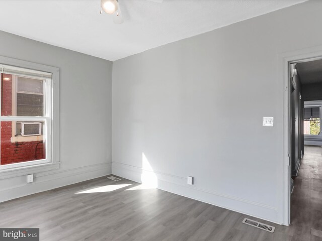 empty room featuring cooling unit, hardwood / wood-style flooring, and ceiling fan