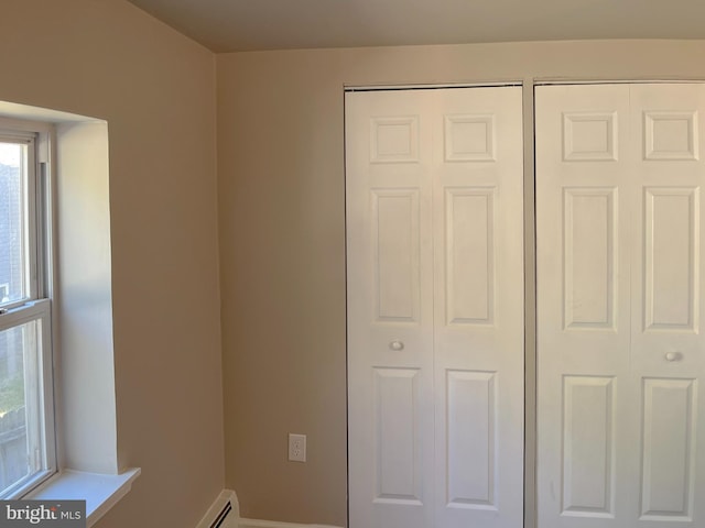 unfurnished bedroom with a baseboard heating unit and two closets