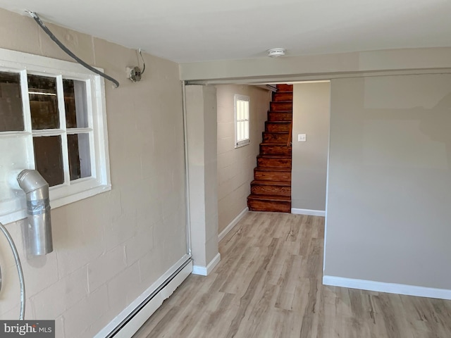 basement with light hardwood / wood-style flooring and a baseboard heating unit